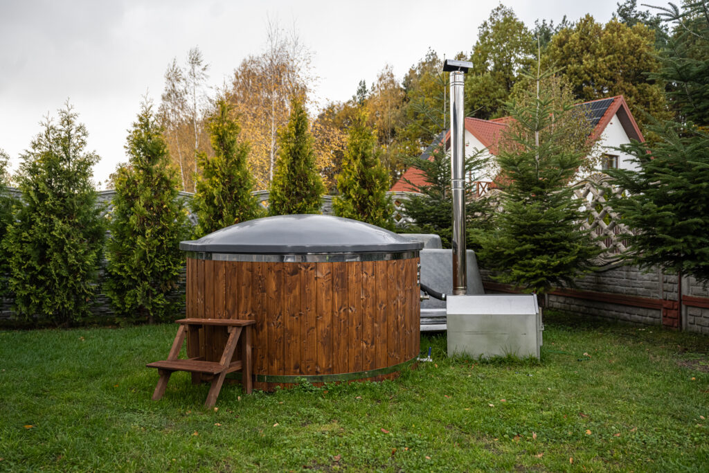 Balia ogrodowa z piecem zewnętrznym i pokrywą w jesiennym ogrodzie przy domu