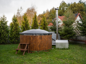 Balia ogrodowa z piecem zewnętrznym i pokrywą w jesiennym ogrodzie przy domu